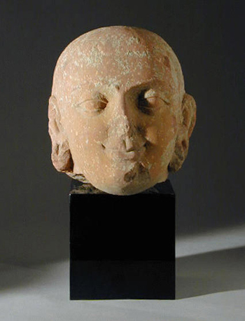 Lot image - Kushan Red Sandstone Head of Buddha Circa 2nd century A.D.  The short ovoid face is detailed with softly rendered mouth and sh